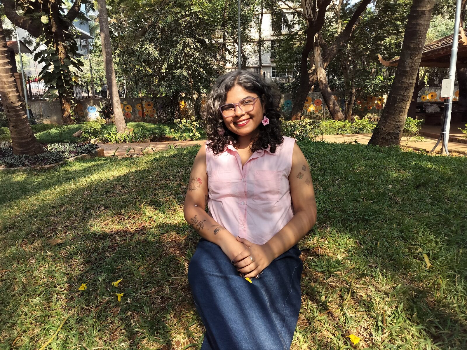 Durva Bhatt sitting on the grass in a garden, smiling at the camera