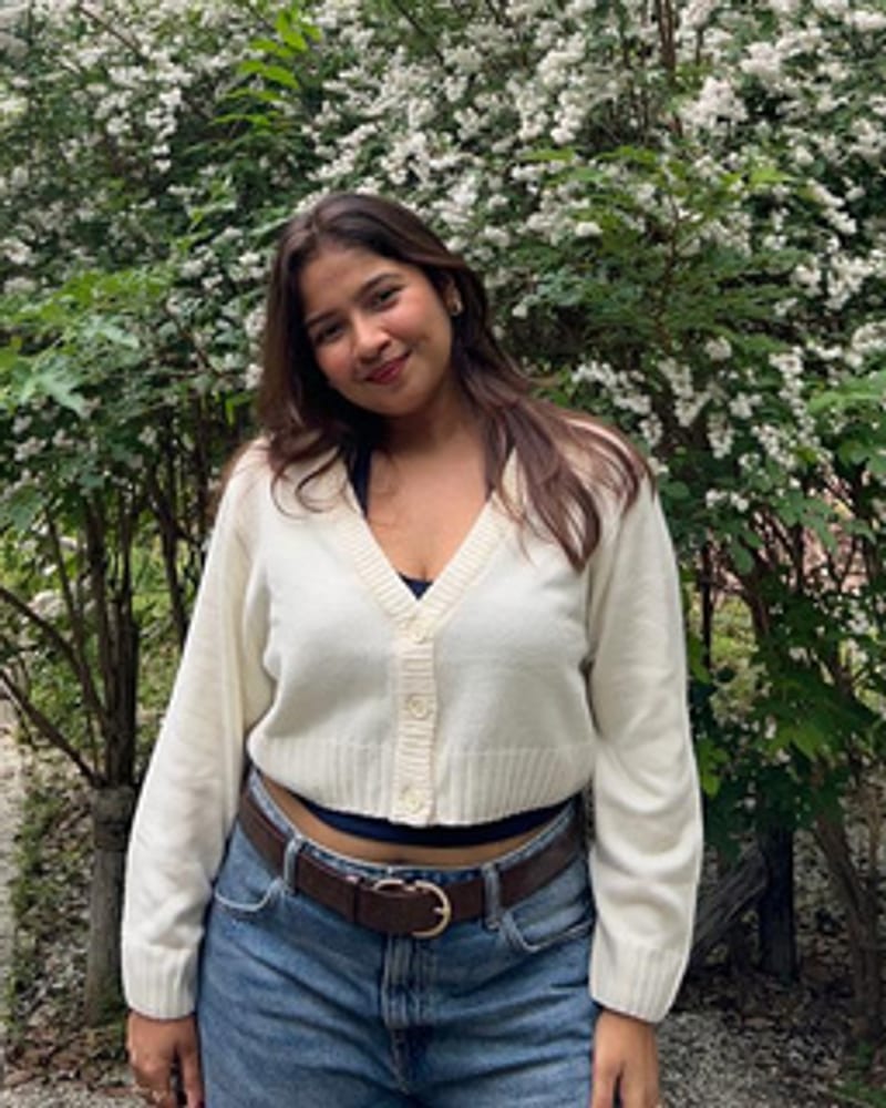 Neeli, standing in front of a flowering hedge